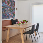 White oak wood table with modern and sleek design and banquette seating with black leather chairs and contemporary modern art